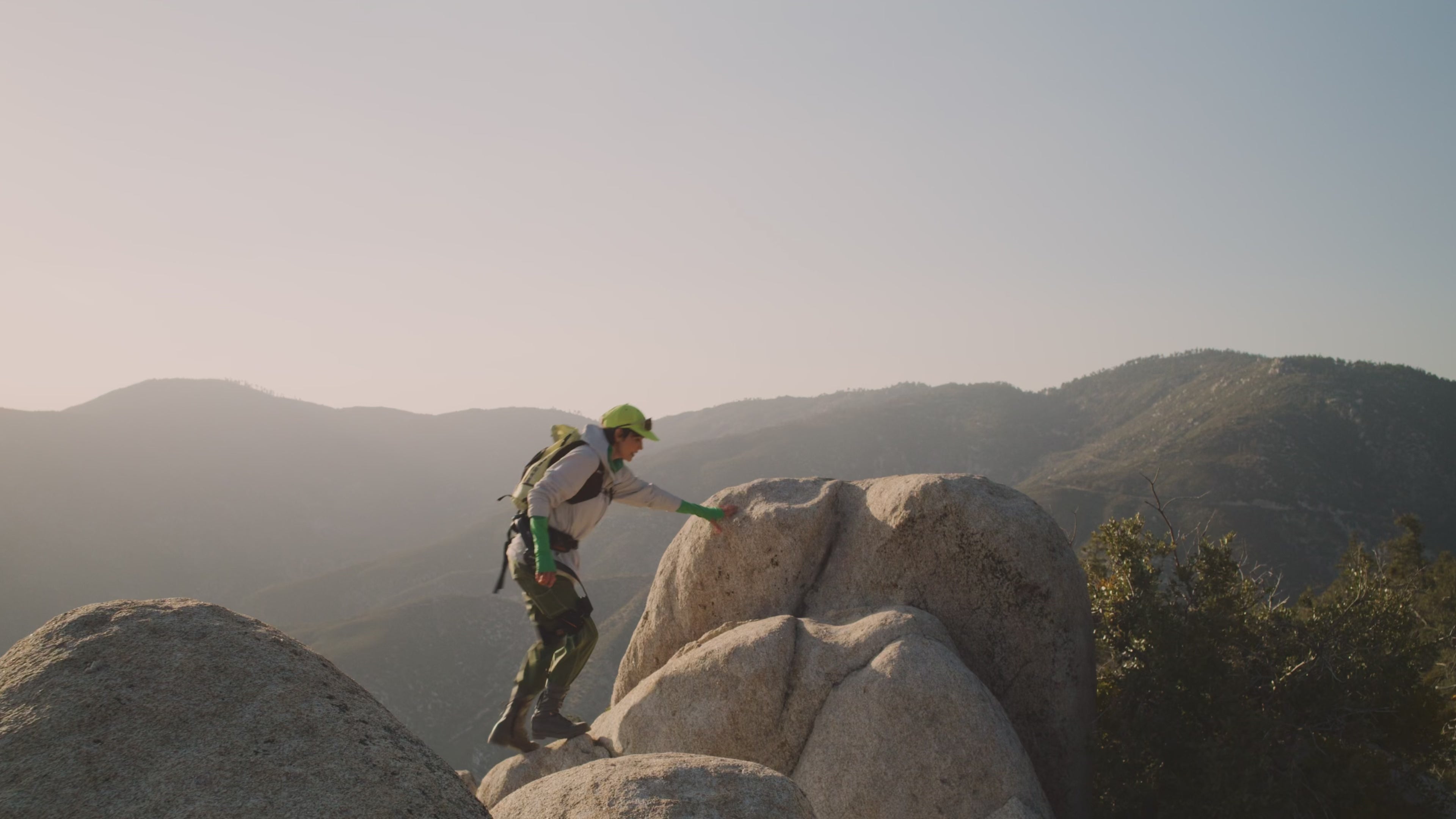 A hiker navigating steep, rocky mountain terrain wearing the New Hypershell X Series exoskeleton Hypershell X Ultra S.