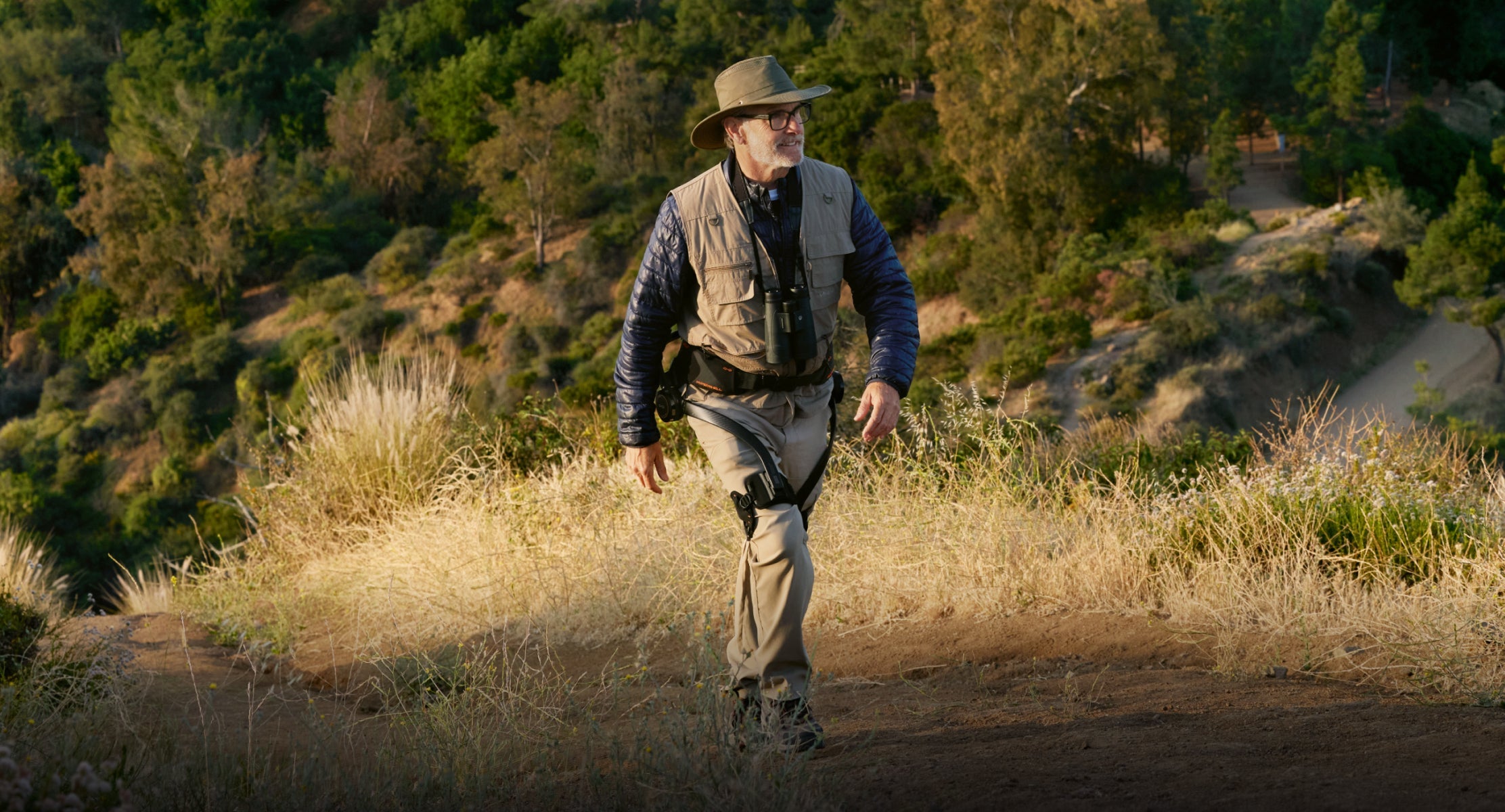 Man walking on a dirt path in a natural landscape with Hypershell X Ultra S Eco Mode (30%)