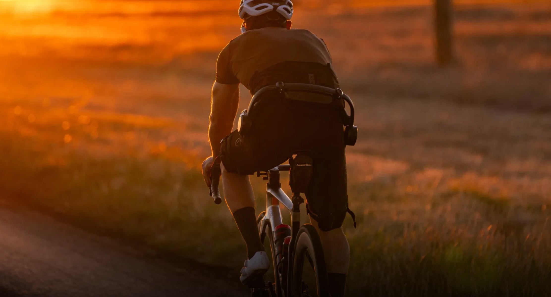 Person cycling on a path during sunset