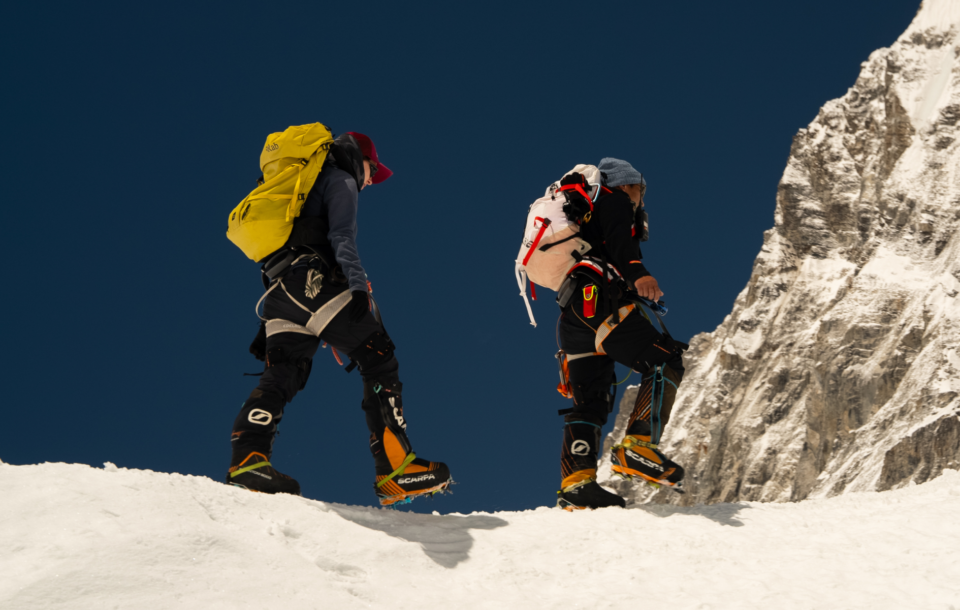 Two hikers wearing Hypershell X Series S exoskeletons on a snowy mountain ridge